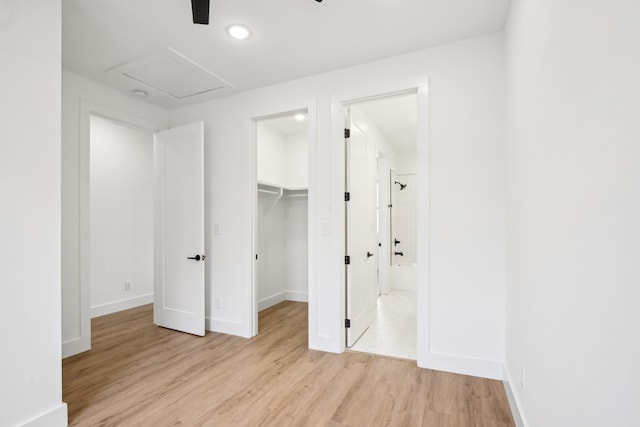 unfurnished bedroom with ensuite bath, a spacious closet, light hardwood / wood-style floors, and a closet