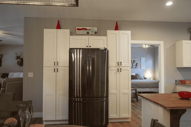 kitchen featuring butcher block counters, white cabinetry, stainless steel refrigerator, hardwood / wood-style flooring, and ceiling fan