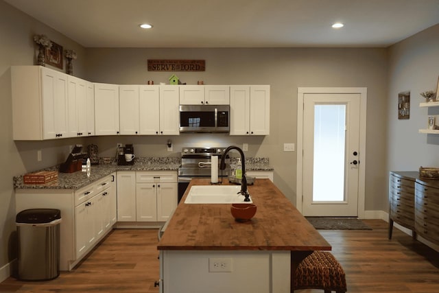 kitchen featuring sink, white cabinetry, dark stone countertops, appliances with stainless steel finishes, and a kitchen island