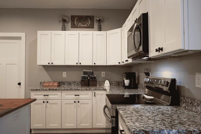 kitchen featuring white cabinetry, stainless steel range with electric cooktop, and dark stone counters