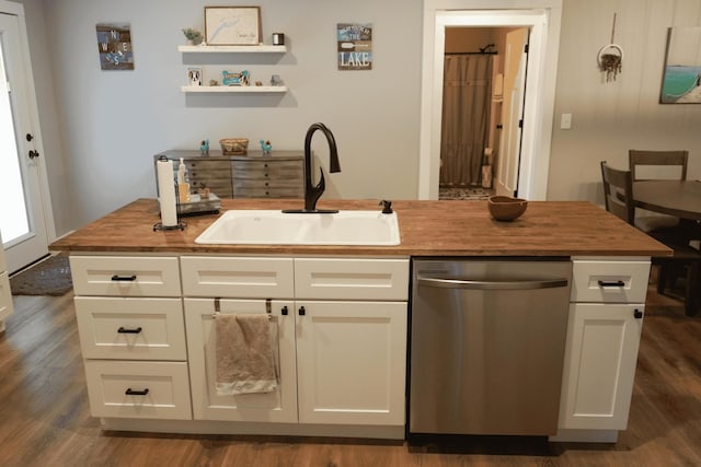 kitchen featuring butcher block countertops, sink, white cabinets, a kitchen island with sink, and stainless steel dishwasher