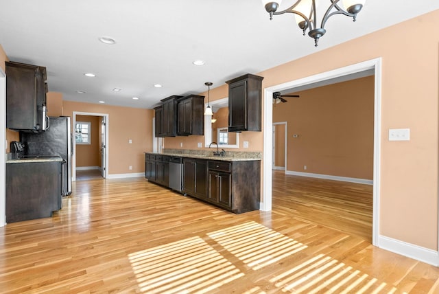 kitchen featuring pendant lighting, dishwasher, sink, light hardwood / wood-style floors, and dark brown cabinets