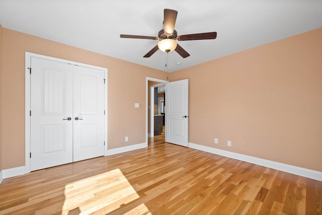 unfurnished bedroom with ceiling fan, light wood-type flooring, and a closet