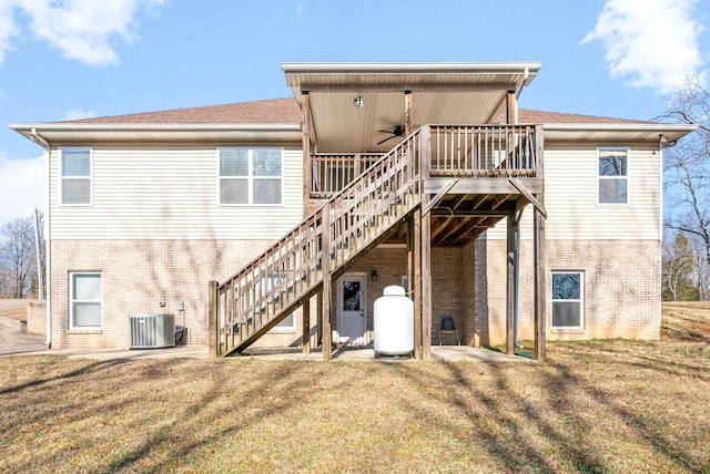 rear view of house featuring a wooden deck, ceiling fan, central AC unit, and a lawn