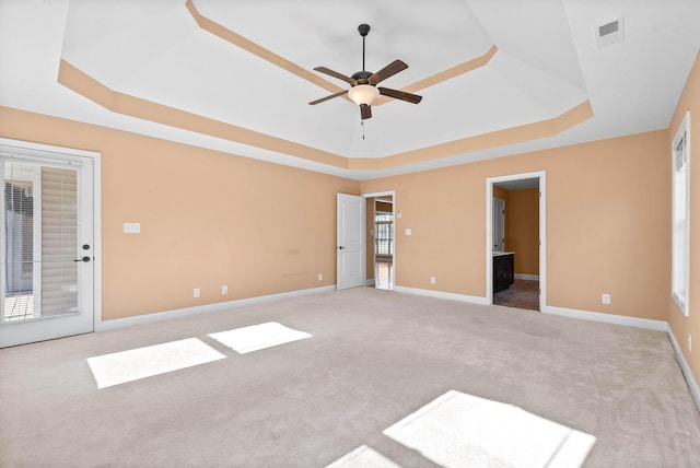 unfurnished room with ceiling fan, a raised ceiling, and light carpet