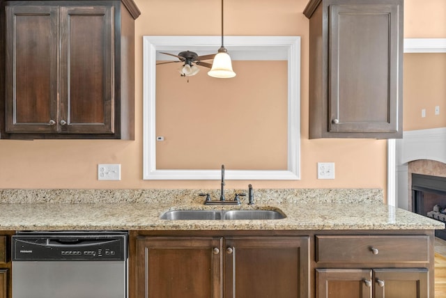 kitchen featuring sink, hanging light fixtures, dark brown cabinets, light stone countertops, and stainless steel dishwasher