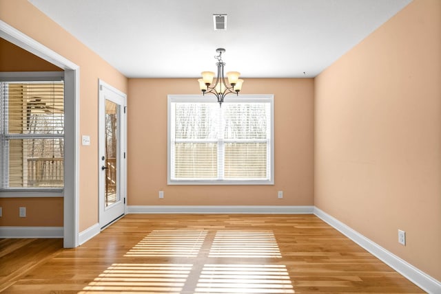 unfurnished dining area with a chandelier and light hardwood / wood-style floors