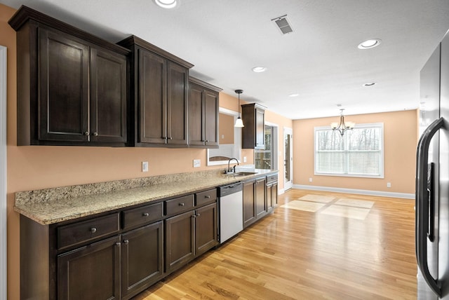 kitchen featuring hanging light fixtures, dishwasher, black fridge, and sink