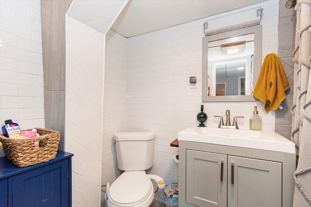 bathroom featuring vanity, tile walls, and toilet