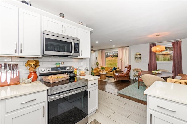 kitchen featuring stainless steel appliances, tasteful backsplash, a healthy amount of sunlight, and white cabinetry