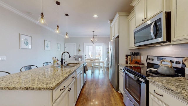 kitchen featuring pendant lighting, appliances with stainless steel finishes, sink, and a center island with sink