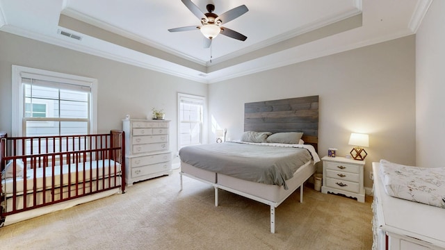 carpeted bedroom with a tray ceiling, ornamental molding, and ceiling fan