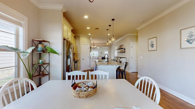 dining area featuring dark wood-type flooring, crown molding, sink, and a notable chandelier