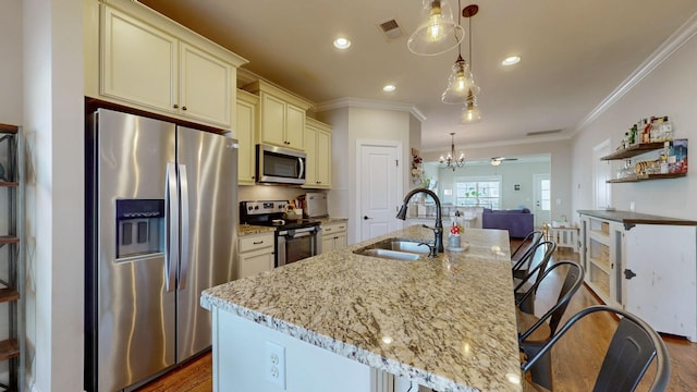 kitchen featuring a kitchen island with sink, sink, decorative light fixtures, and stainless steel appliances