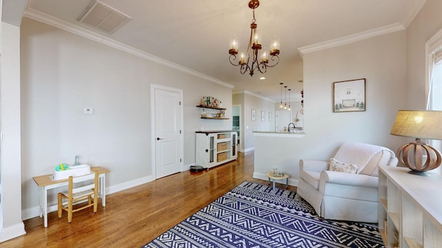 living area featuring hardwood / wood-style flooring, ornamental molding, and a notable chandelier