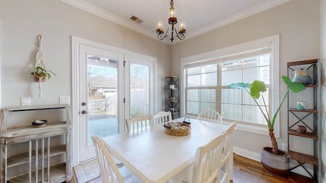 dining space with crown molding, light hardwood / wood-style floors, and a chandelier