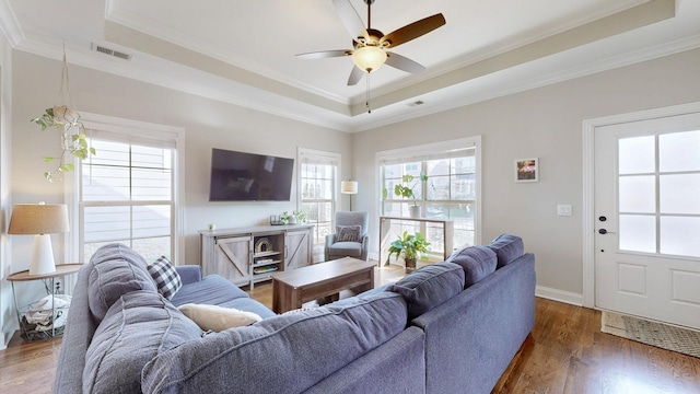 living room featuring ceiling fan, ornamental molding, a tray ceiling, and dark hardwood / wood-style flooring