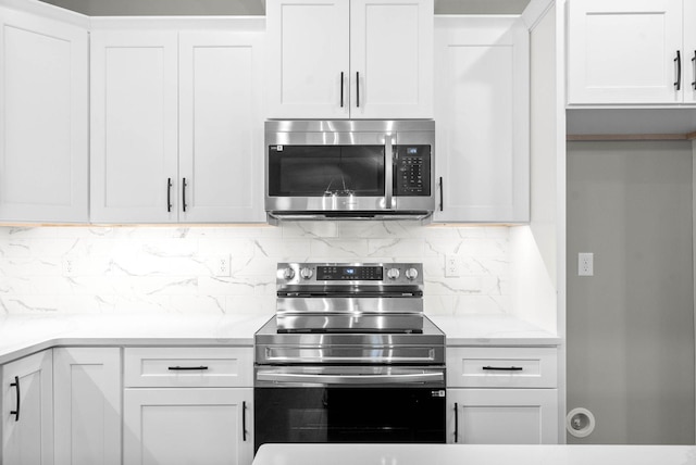 kitchen with stainless steel appliances, tasteful backsplash, light stone countertops, and white cabinets