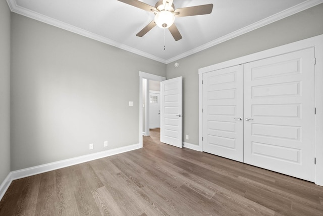 unfurnished bedroom with ornamental molding, hardwood / wood-style floors, ceiling fan, and a closet