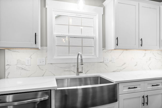 kitchen with light stone counters, dishwasher, sink, and white cabinets