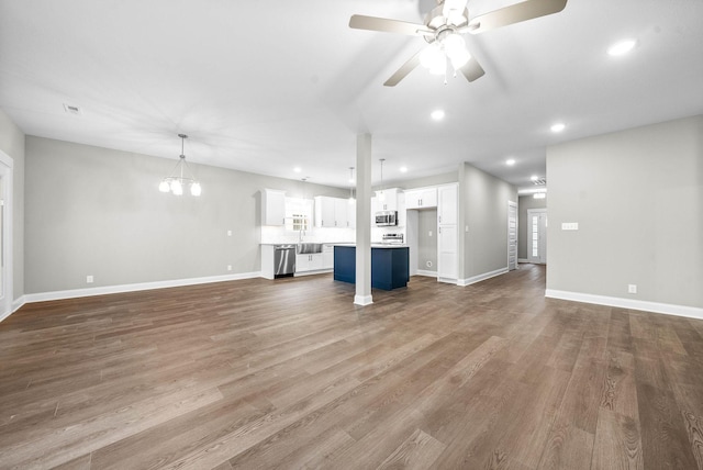 unfurnished living room with ceiling fan with notable chandelier and hardwood / wood-style floors