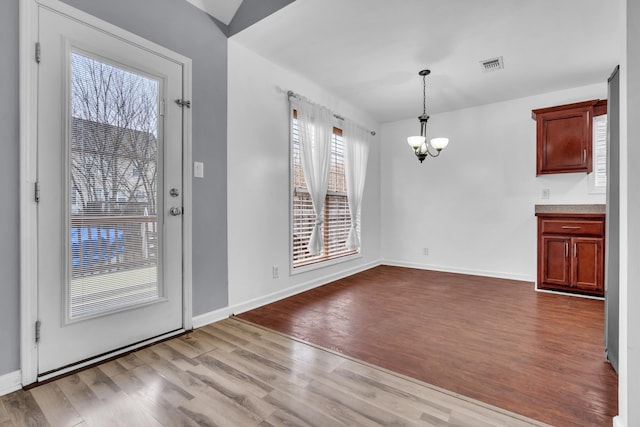 unfurnished dining area featuring light wood-type flooring and an inviting chandelier