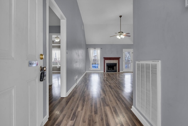 unfurnished living room with a tile fireplace, ceiling fan, lofted ceiling, and dark hardwood / wood-style flooring