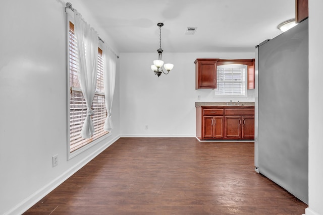 unfurnished dining area with sink, a notable chandelier, and dark hardwood / wood-style flooring