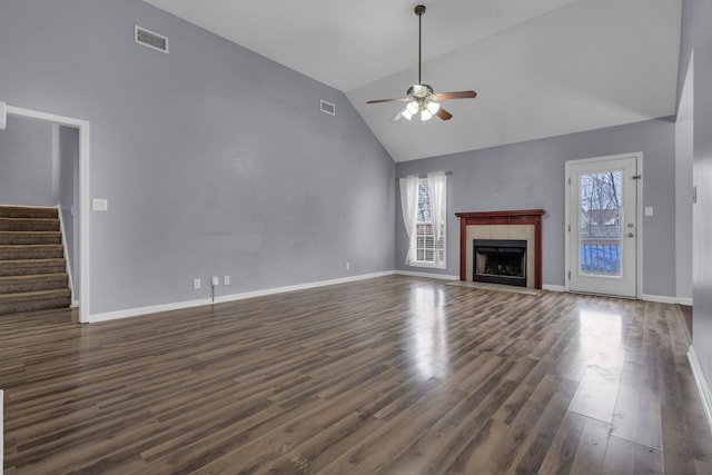 unfurnished living room with dark hardwood / wood-style flooring, ceiling fan, high vaulted ceiling, and a tiled fireplace