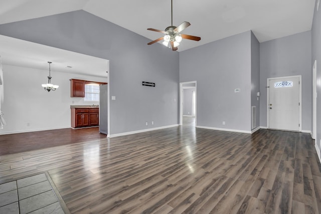 unfurnished living room featuring ceiling fan with notable chandelier, high vaulted ceiling, and dark hardwood / wood-style floors