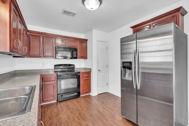 kitchen with sink, dark wood-type flooring, and black appliances