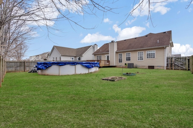 rear view of house with a covered pool, central AC unit, and a lawn