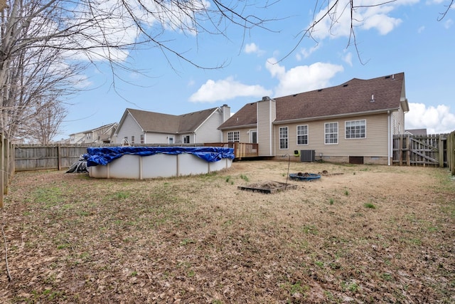 back of property with a swimming pool side deck, central air condition unit, and a yard