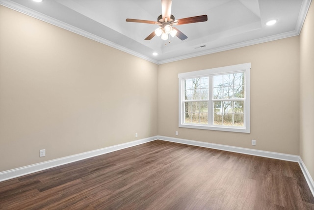 unfurnished room with ornamental molding, dark wood-type flooring, ceiling fan, and a tray ceiling