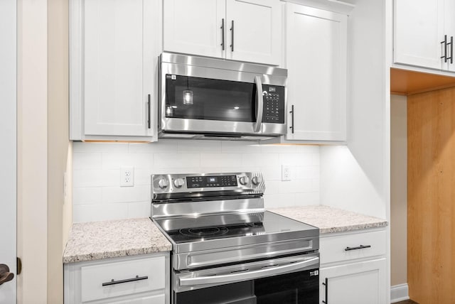 kitchen featuring white cabinetry, stainless steel appliances, and light stone counters