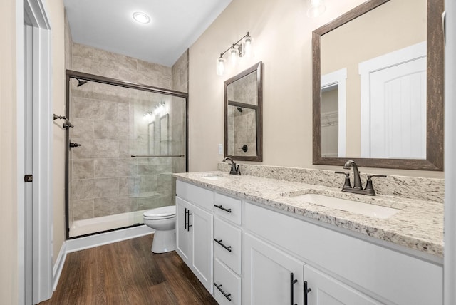 bathroom with hardwood / wood-style flooring, vanity, toilet, and a shower with shower door