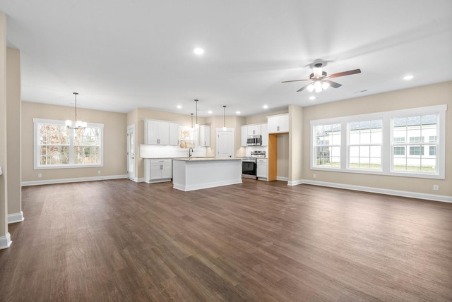 unfurnished living room with sink, ceiling fan with notable chandelier, and dark hardwood / wood-style flooring