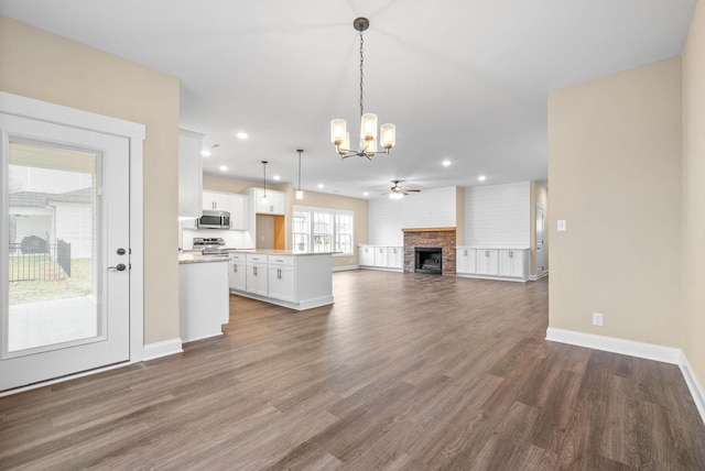 kitchen featuring appliances with stainless steel finishes, hanging light fixtures, white cabinets, dark hardwood / wood-style flooring, and ceiling fan with notable chandelier