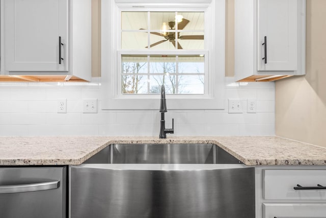 kitchen featuring tasteful backsplash, sink, light stone countertops, and white cabinets