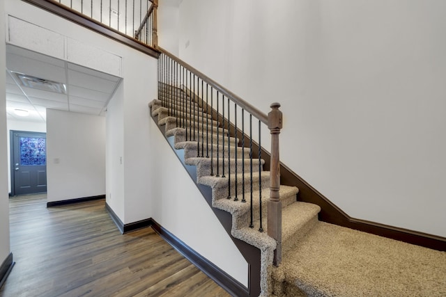 stairs featuring a drop ceiling and hardwood / wood-style flooring