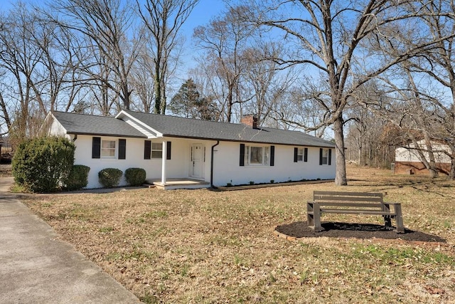 single story home featuring covered porch, roof with shingles, a front lawn, and a chimney