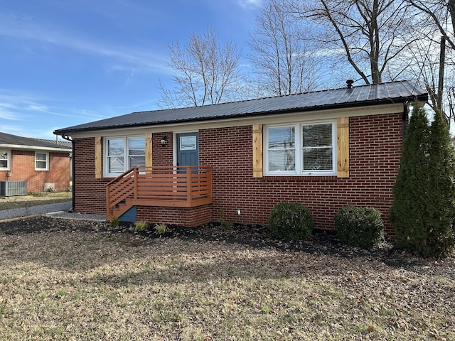 view of front of home with metal roof, brick siding, and central air condition unit