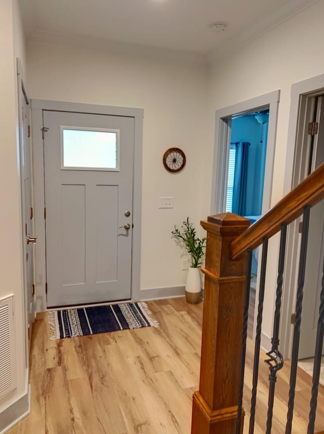 entrance foyer with ornamental molding and light hardwood / wood-style flooring