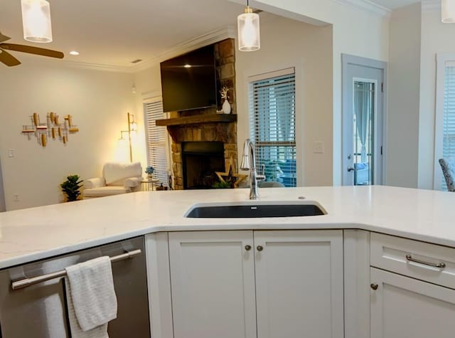 kitchen with stainless steel dishwasher, pendant lighting, ornamental molding, sink, and white cabinetry