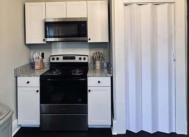 kitchen with stainless steel appliances, white cabinets, and light stone counters