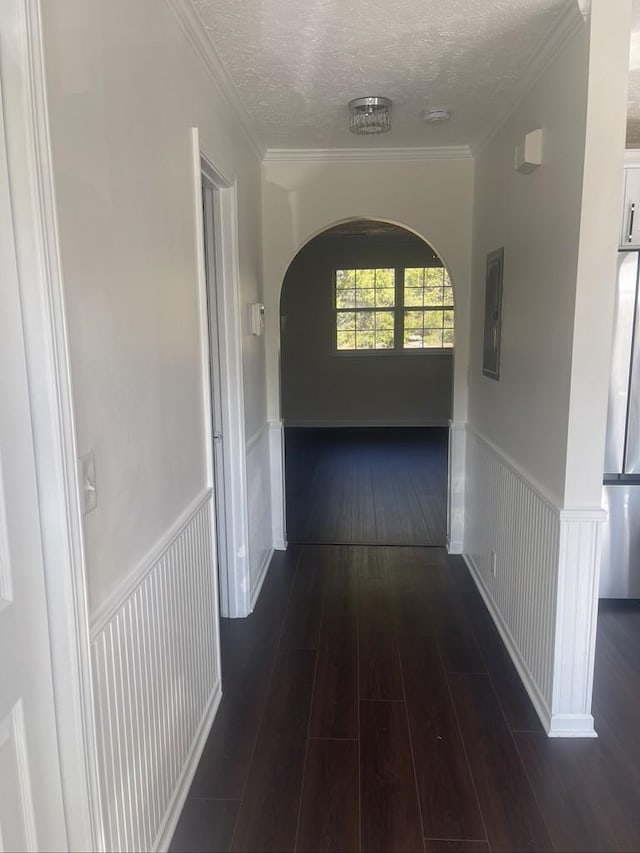 hallway with dark wood-type flooring, crown molding, and a textured ceiling