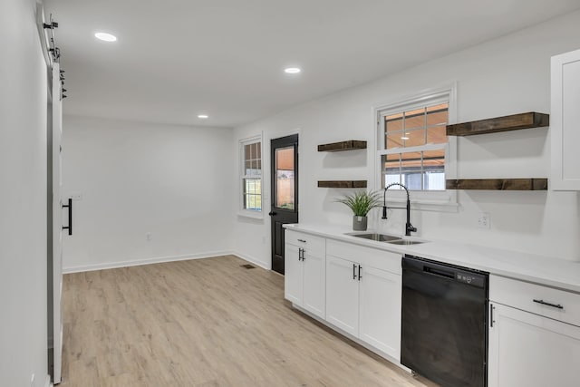 kitchen with white cabinetry, black dishwasher, sink, and light wood-type flooring