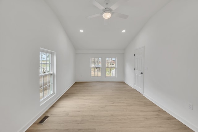 spare room featuring plenty of natural light, high vaulted ceiling, ceiling fan, and light hardwood / wood-style flooring