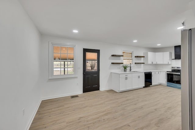 kitchen with sink, white cabinetry, stainless steel appliances, light hardwood / wood-style floors, and wall chimney exhaust hood