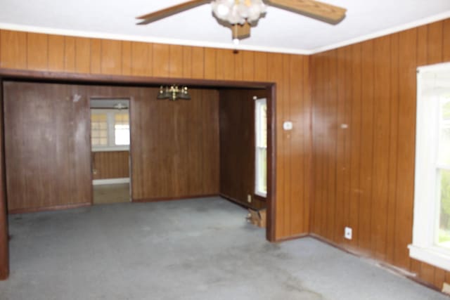 entryway featuring crown molding, wood walls, ceiling fan with notable chandelier, and light carpet